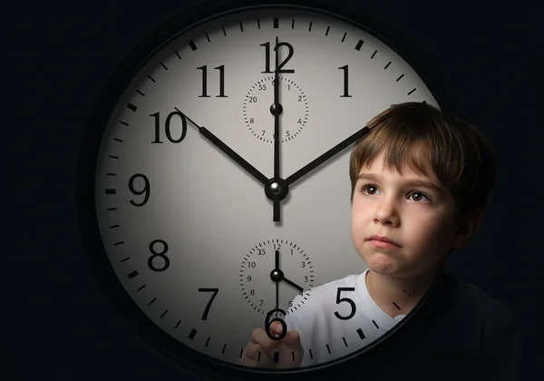 Child looking confused at complex analog clock.