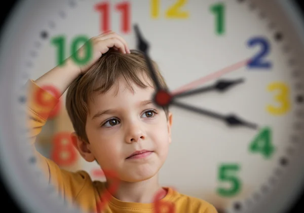 Child confused by analog clock hands, showing frustration